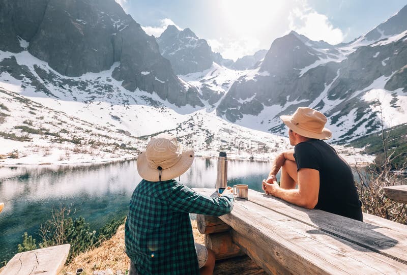 Otec a syn pěší turistika odpočívají a pijí čaj poblíž hory