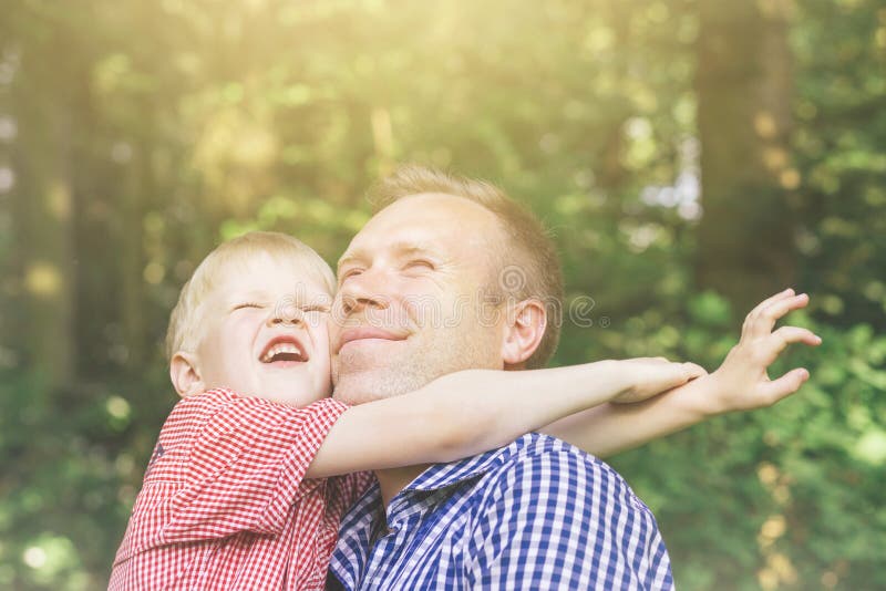 Father and son hugging and looking at the sun.