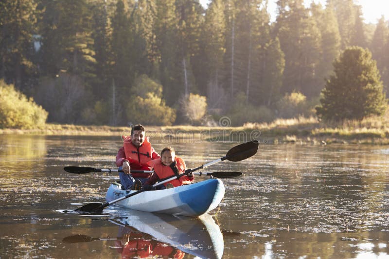 Father and son kayaking on rural lake, front view stock images