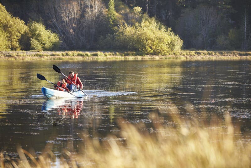 Father and son kayaking together on a lake, front view royalty free stock image