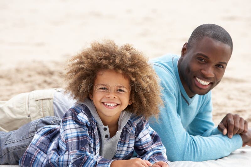 Father and son laying on beach