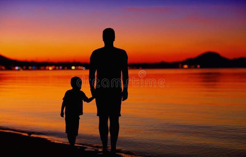 Father and son near the water edge at sunset