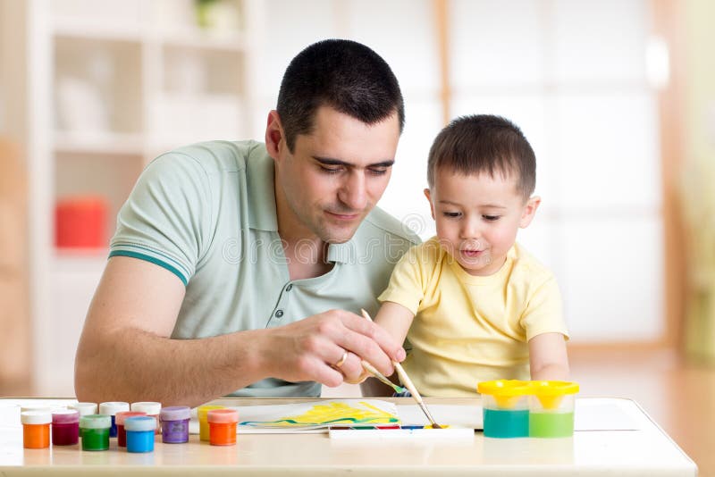 Father and little son are painting together. Happy family are coloring with paintbrush. Man and child have a fun pastime.