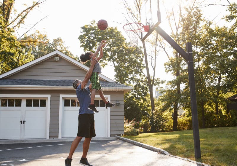Father And Son Playing Basketball On Driveway At Home stock photo