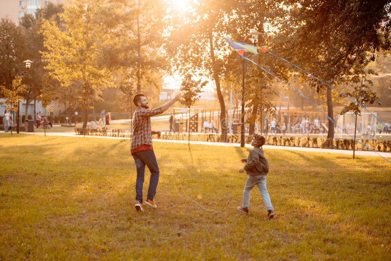 Father and son playing with a kite in an autumn park on a stock image Father and son playing with a kite in an autumn park on a stock image