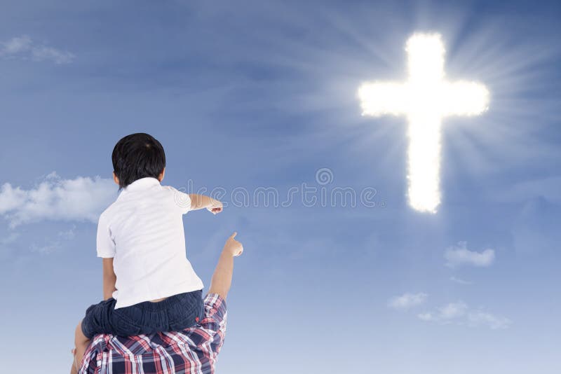 Father and son pointing at cross on the blue sky