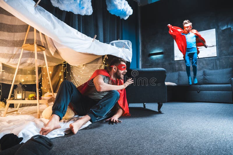 Father and son in red superhero costumes playing stock photography Father and son in red superhero costumes playing stock photography