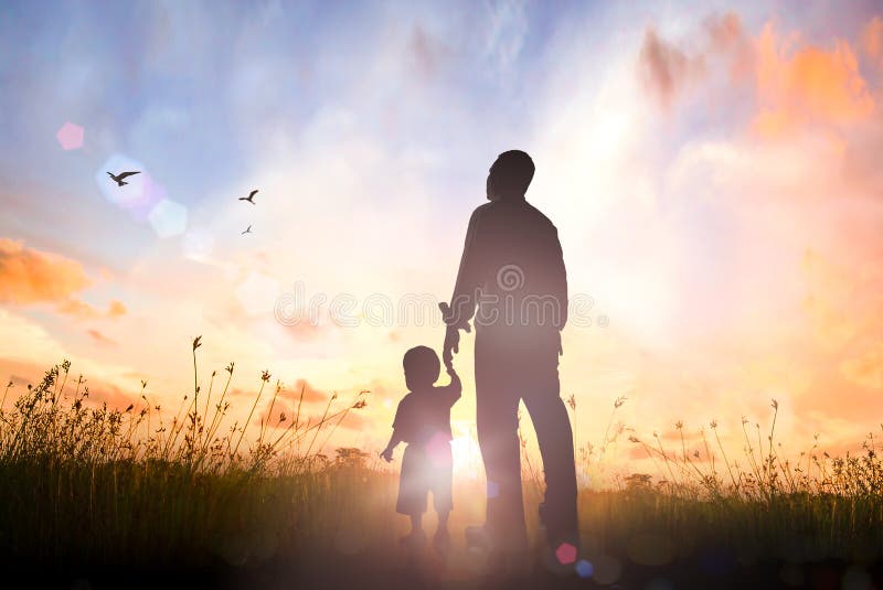 Happy Father`s Day concept: Silhouette Father and son standing on meadow autumn sunrise background