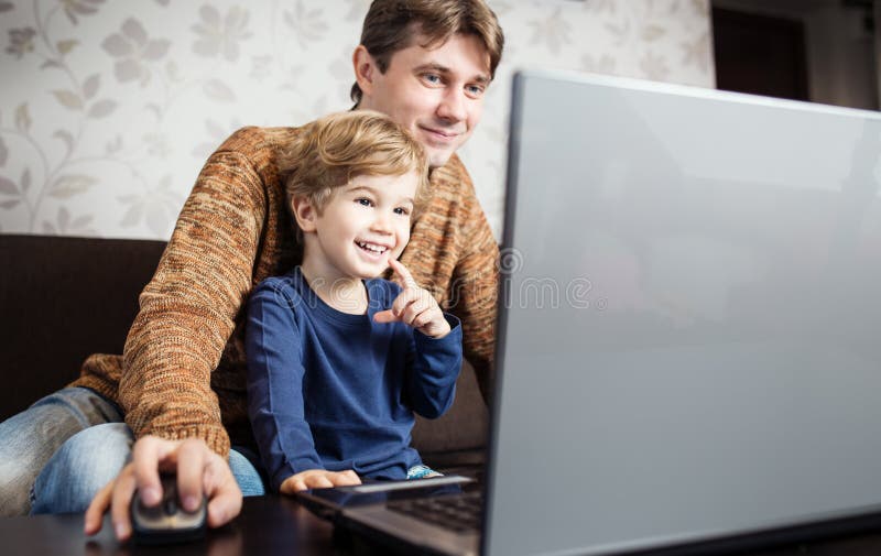 Father and son using laptop on sofa royalty free stock photos Father and son using laptop on sofa royalty free stock photos