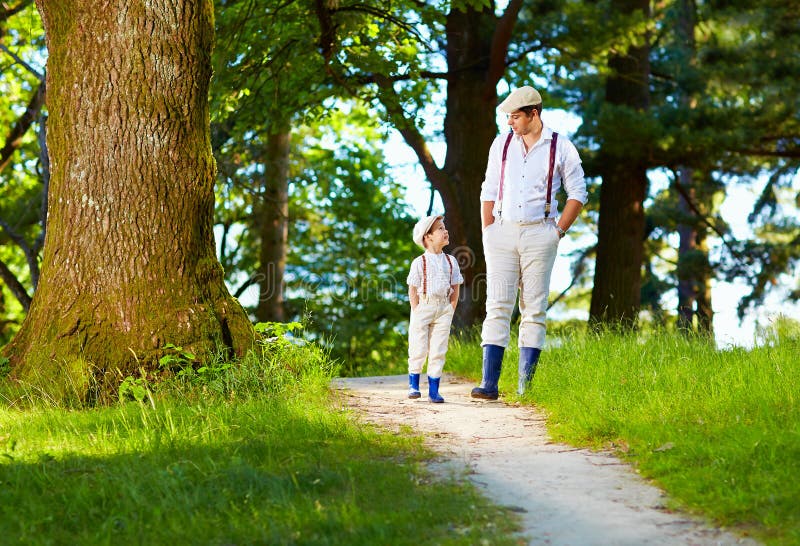 Father and son walking rural path in forest