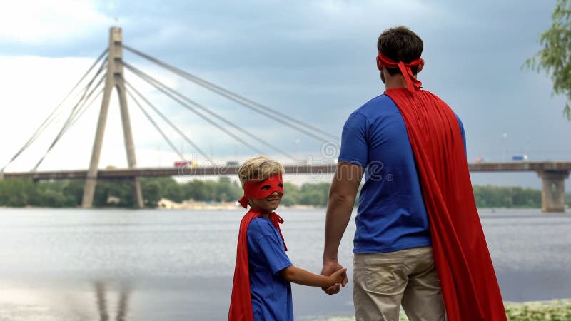 Father and son wearing funny superhero costumes looking afar, supportive parent stock images Father and son wearing funny superhero costumes looking afar, supportive parent stock images
