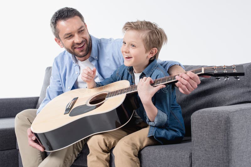 Smiling father teaching his excited son to sing and play on guitar