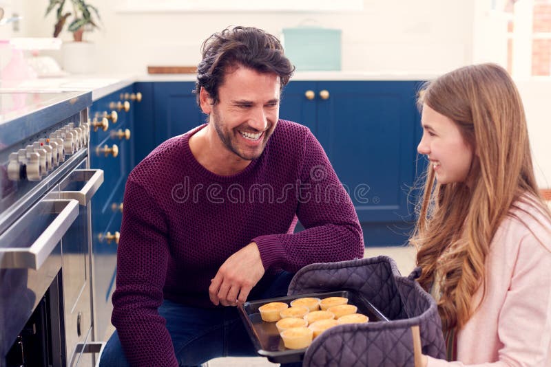 Father with Teenage Daughter Taking Out Freshly Baked Homemade Cupca picture photo