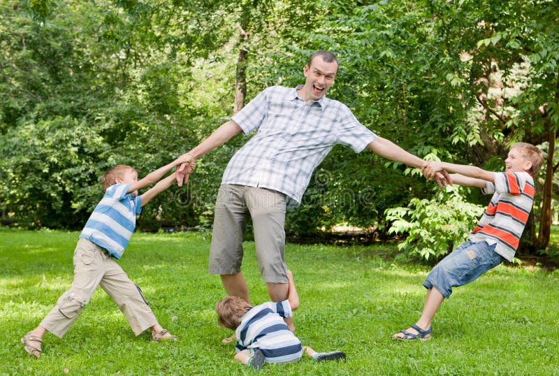 Father and three sons play in the park.