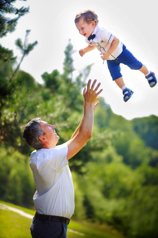 Father threw his son very high. A child against the sky above the hands of dad. A happy child flies up over the pines. Walking in