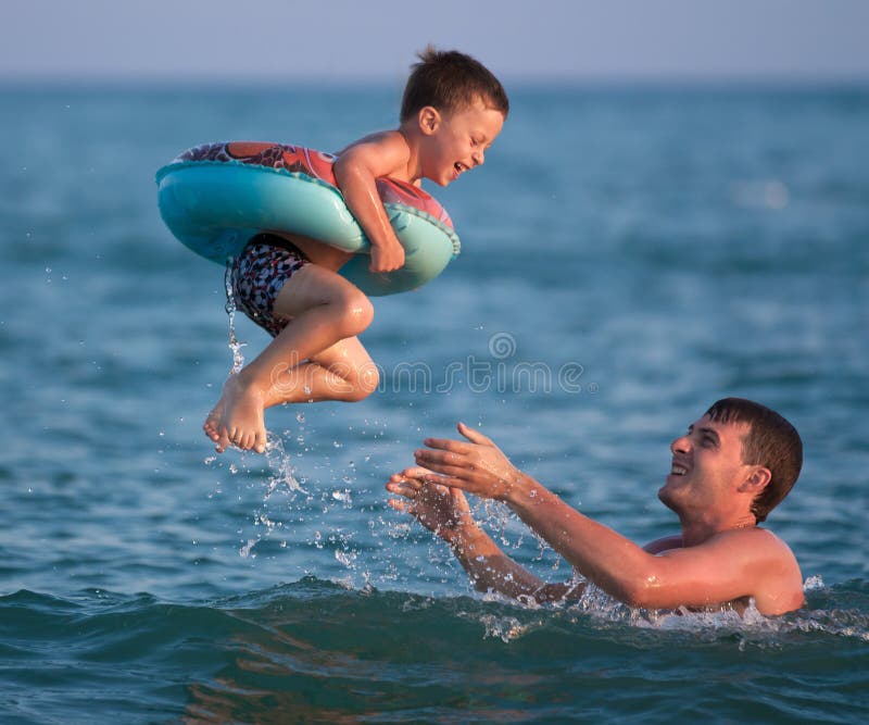 Father Throws Up His Son in an Inflatable Circle Under the Sea Stock