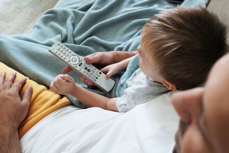 Father and toddler are watching television together and switching the new programme with a remote control royalty free stock image Father and toddler are watching television together and switching the new programme with a remote control royalty free stock image
