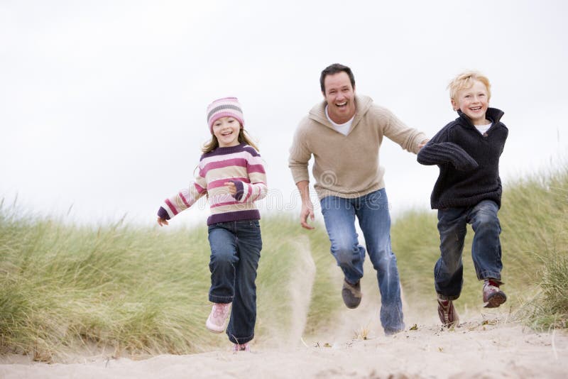 Father and two young children running at beach