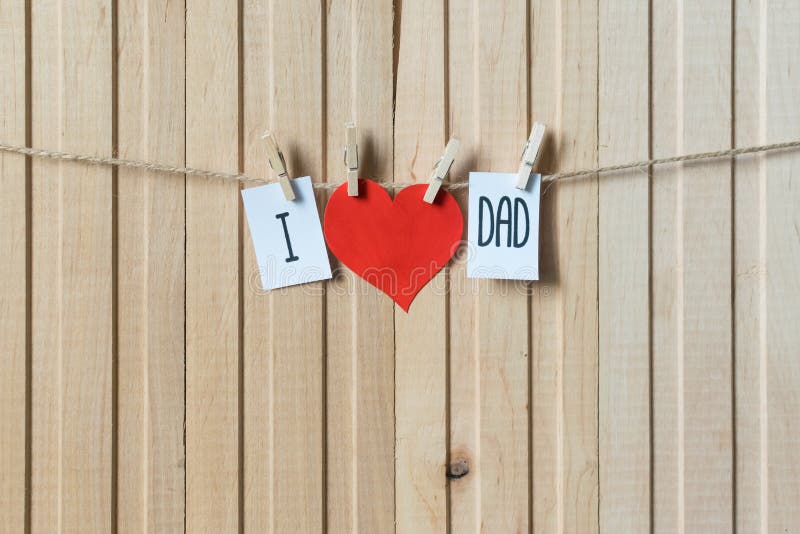 Fathers day concept. Message with paper heart hanging with pins over light wooden board. Happy Birthday