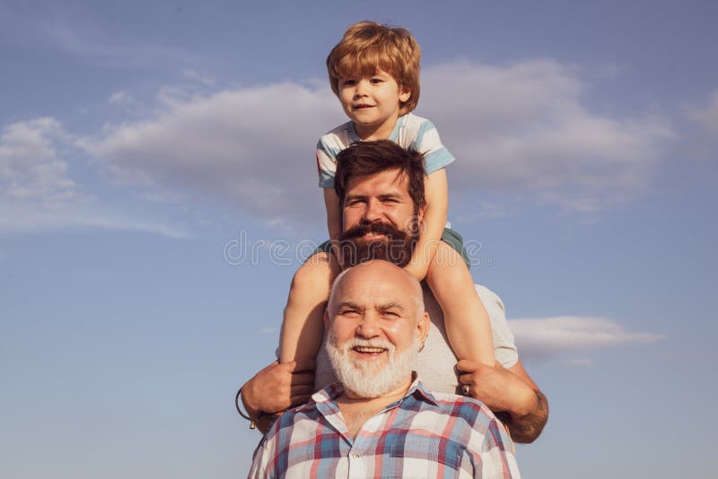 Fathers day - grandfather, father and son are hugging and having fun together. Happy child playing against summer sky