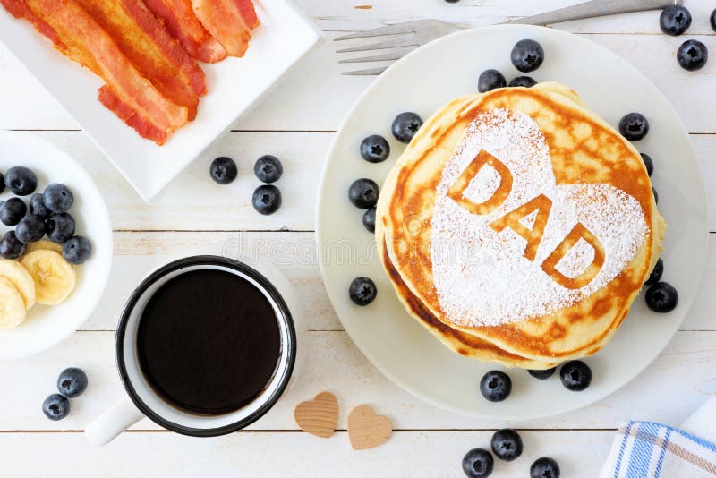 Fathers Day pancake breakfast with heart shape and DAD letters, above view table scene on white wood