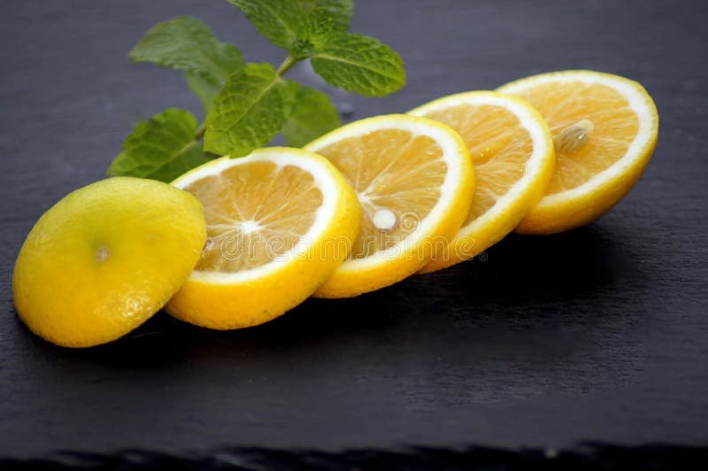 Fatias do limão com a hortelã na placa da ardósia fotos de stock royalty free