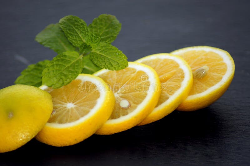 Fatias do limão com a hortelã na placa da ardósia fotos de stock royalty free
