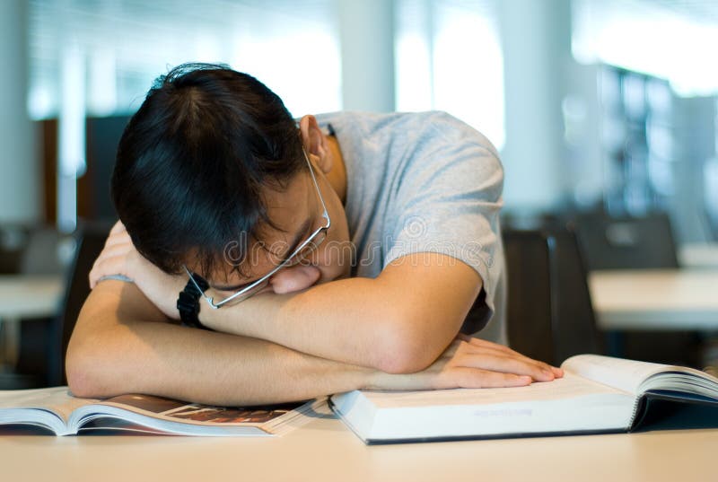 Adolescente ragazzo affaticati dalla sua ricerca in una biblioteca.