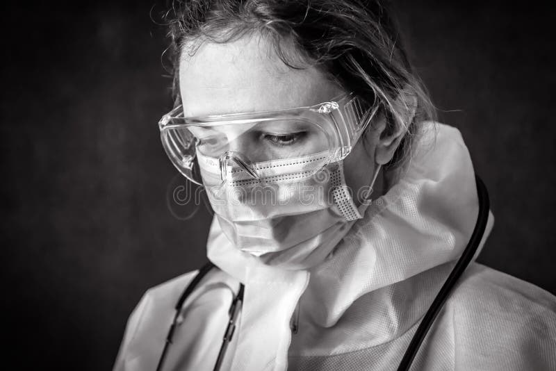 Tired exhausted doctor in personal protective equipment PPE, nurse wearing medical glasses and face mask, portrait of woman in professional suit due to COVID-19 coronavirus. Hospital care concept. Tired exhausted doctor in personal protective equipment PPE, nurse wearing medical glasses and face mask, portrait of woman in professional suit due to COVID-19 coronavirus. Hospital care concept