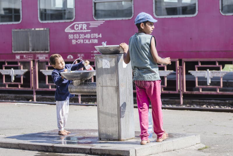 Two poor homeless boys filling bottles of water at the railway station in Craiova, Romania. Two poor homeless boys filling bottles of water at the railway station in Craiova, Romania.