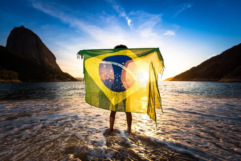Fată care deține steagul brazilian pe plajă royalty free stock photo