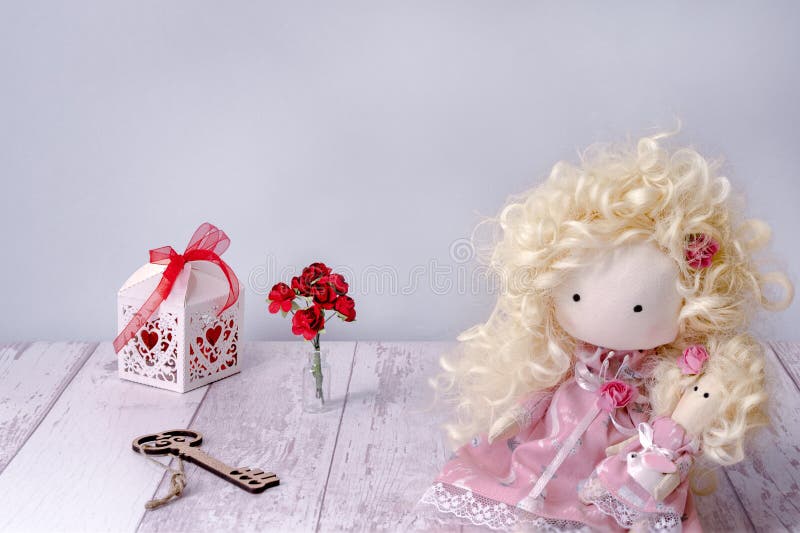 Fată de jucărie din material de mână într-un spațiu alb pentru copii pe o masă de lemn cu hârtie cu cheie de zâne, cu un trandafir stock images