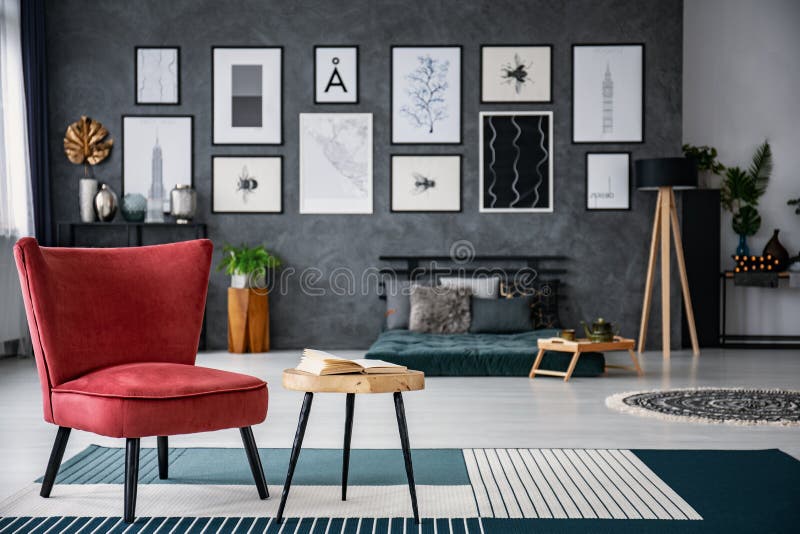 Fauteuil rouge à côté de table sur le tapis dans l'intérieur gris-foncé de salon avec la galerie à l'arrière-plan brouillé Photo image stock Fauteuil rouge à côté de table sur le tapis dans l'intérieur gris-foncé de salon avec la galerie à l'arrière-plan brouillé Photo image stock
