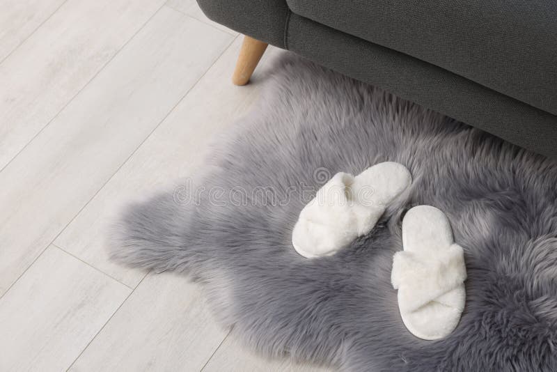 Faux Fur Rug with Slippers on Floor in Room, Space for Text Stock Photo