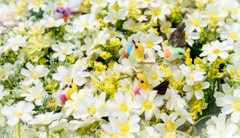 Faux oiseaux colorés parmi les fleurs blanches artificielles images libres de droits