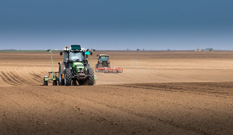 Fazendeiro com o trator que semeia semeando colheitas no campo agr?cola imagens de stock Fazendeiro com o trator que semeia semeando colheitas no campo agr?cola imagens de stock