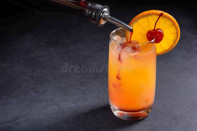Fazendo o cocktail do nascer do sol do tequila O xarope de groselha derramou lentamente em um vidro do gelo, do suco de laranja e fotografia de stock royalty free Fazendo o cocktail do nascer do sol do tequila O xarope de groselha derramou lentamente em um vidro do gelo, do suco de laranja e fotografia de stock royalty free