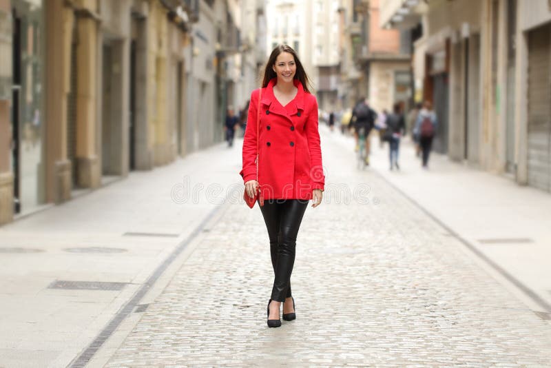 Façonnez la femme dans la marche rouge sur une rue de ville images stock Façonnez la femme dans la marche rouge sur une rue de ville images stock