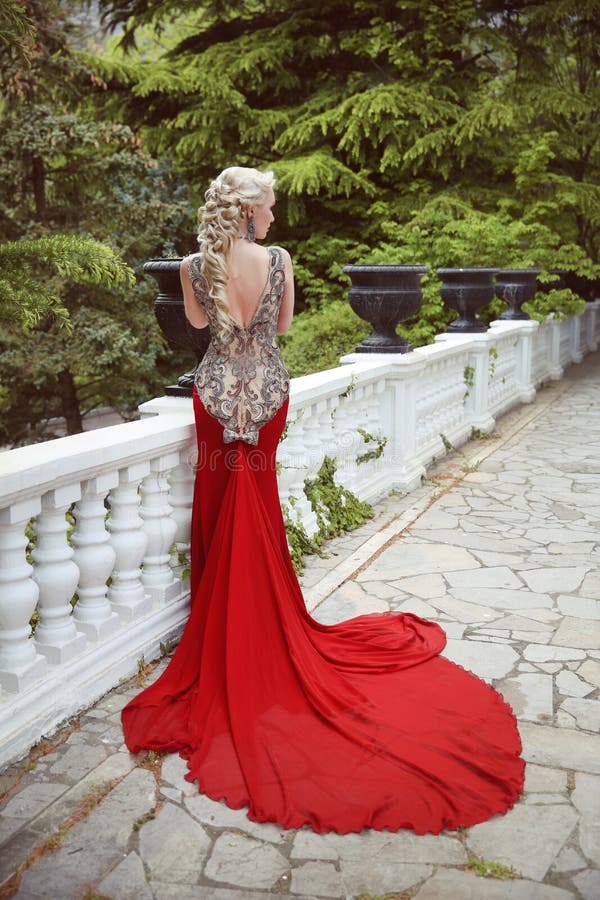 Façonnez le modèle blond élégant de femme dans la robe rouge avec le long train de photos stock Façonnez le modèle blond élégant de femme dans la robe rouge avec le long train de photos stock