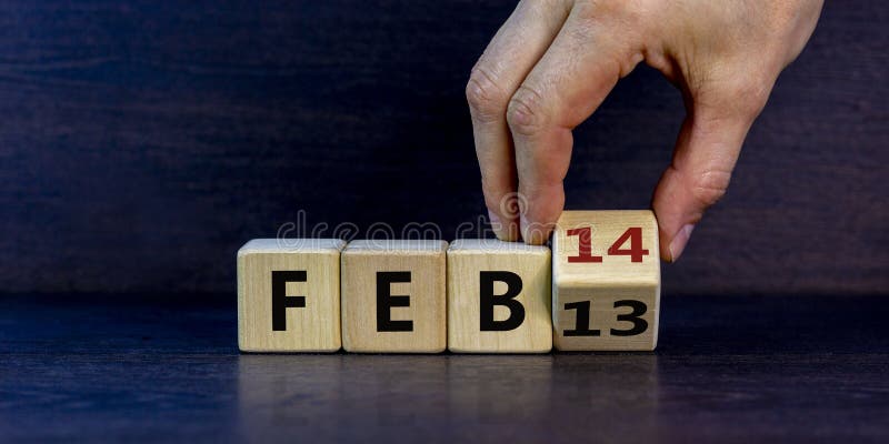 February 14 valentines day symbol. Hand turns the cube and changes the word `Feb 13` to `Feb 14`. Beautiful grey background, copy space. February 14 Valentines day concept. February 14 valentines day symbol. Hand turns the cube and changes the word `Feb 13` to `Feb 14`. Beautiful grey background, copy space. February 14 Valentines day concept.