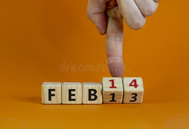February 14 valentines day symbol. Hand turns the cube and changes the word `Feb 13` to `Feb 14`. Beautiful orange background, copy space. February 14 Valentines day concept. February 14 valentines day symbol. Hand turns the cube and changes the word `Feb 13` to `Feb 14`. Beautiful orange background, copy space. February 14 Valentines day concept.