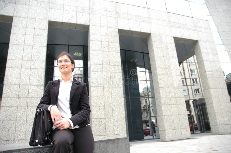 Young business woman waiting in front of a corporate building. Looks like she is meeting with a corporate partner. Conceptual shot for future partnerships. Young business woman waiting in front of a corporate building. Looks like she is meeting with a corporate partner. Conceptual shot for future partnerships.