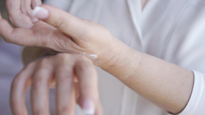 Fechamento de uma mulher madura com manicura francesa aplicando creme branco nas mãos Cuidados corporais, conceito de cuidados cu