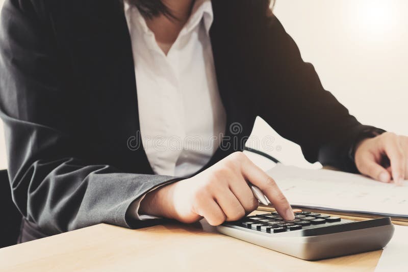Fechar a Mulher de Negócios usando calculadora e laptop para fazer matemática financiando em uma mesa de madeira no escritório e fotos de stock Fechar a Mulher de Negócios usando calculadora e laptop para fazer matemática financiando em uma mesa de madeira no escritório e fotos de stock