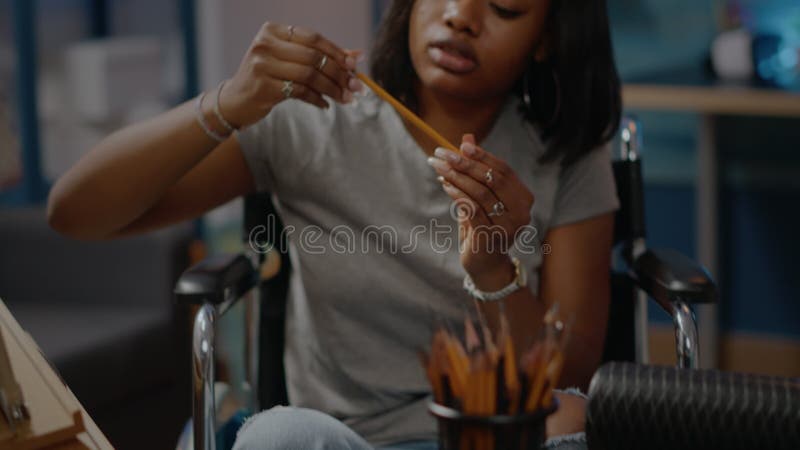 Fechar sobre a mesa o artista e lápis africanos deficientes