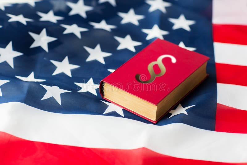 Justice, law, civil rights and nationalism concept - close up of american flag and lawbook. Justice, law, civil rights and nationalism concept - close up of american flag and lawbook