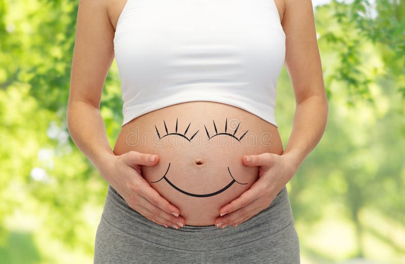 Feche acima da barriga da mulher gravida com smiley