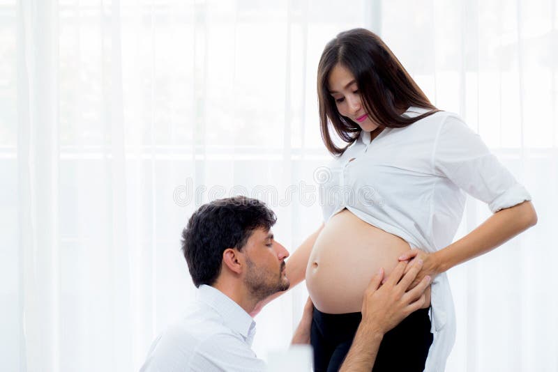 Feche acima da barriga da mulher gravida do beijo do marido - amor do pai ao nascituro imagem de stock royalty free Feche acima da barriga da mulher gravida do beijo do marido - amor do pai ao nascituro imagem de stock royalty free