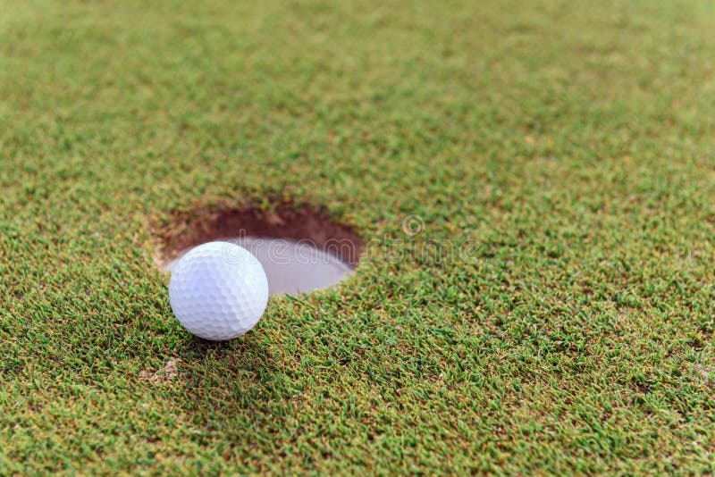 Feche acima da bola de golfe perto do furo fotos de stock royalty free