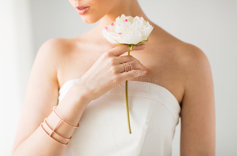 Glamour, beauty, jewelry and luxury concept - close up of beautiful woman with golden ring and bracelet holding flower. Glamour, beauty, jewelry and luxury concept - close up of beautiful woman with golden ring and bracelet holding flower